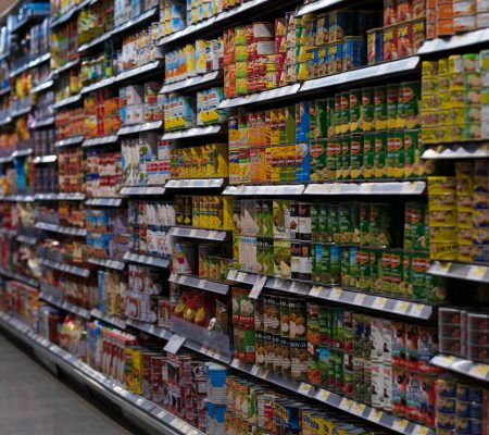 A supermarket aisle filled with various canned goods on shelves, showcasing retail diversity.