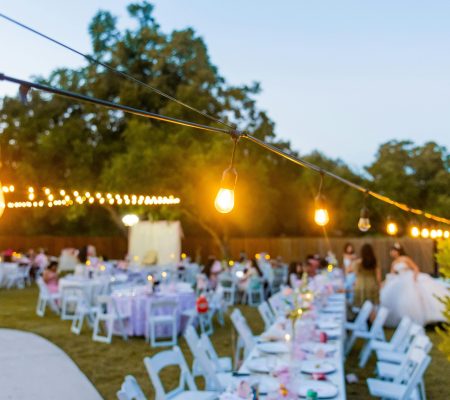 Charming outdoor wedding reception at sunset with string lights.